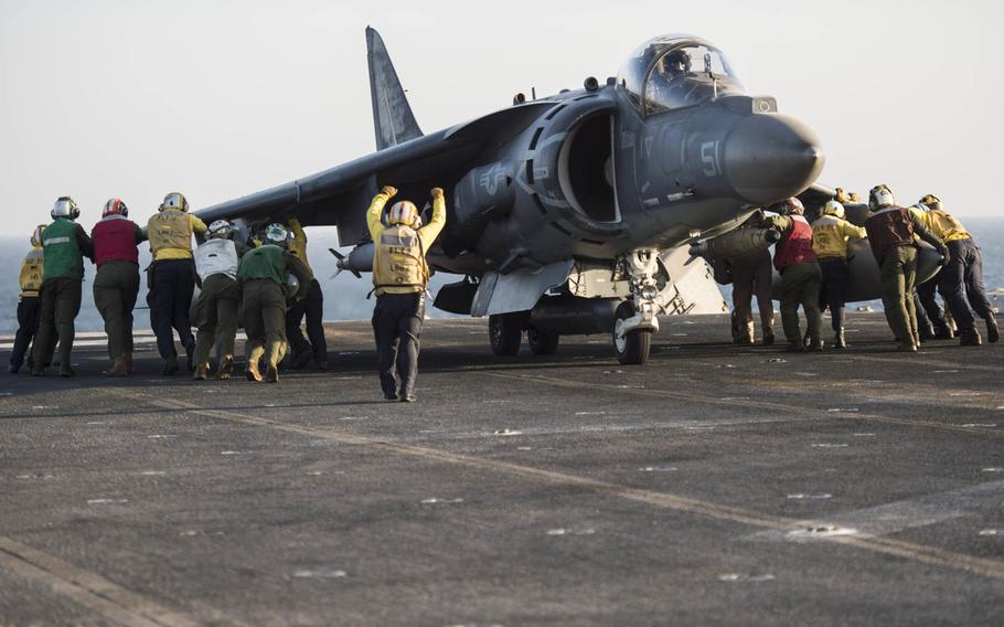 The flight deck crew of the multipurpose amphibious assault ship USS Essex helps turn and push an AV-8B harrier belonging to the 15th Marine Expeditionary Unit into position prior to launching Oct. 13, 2015.