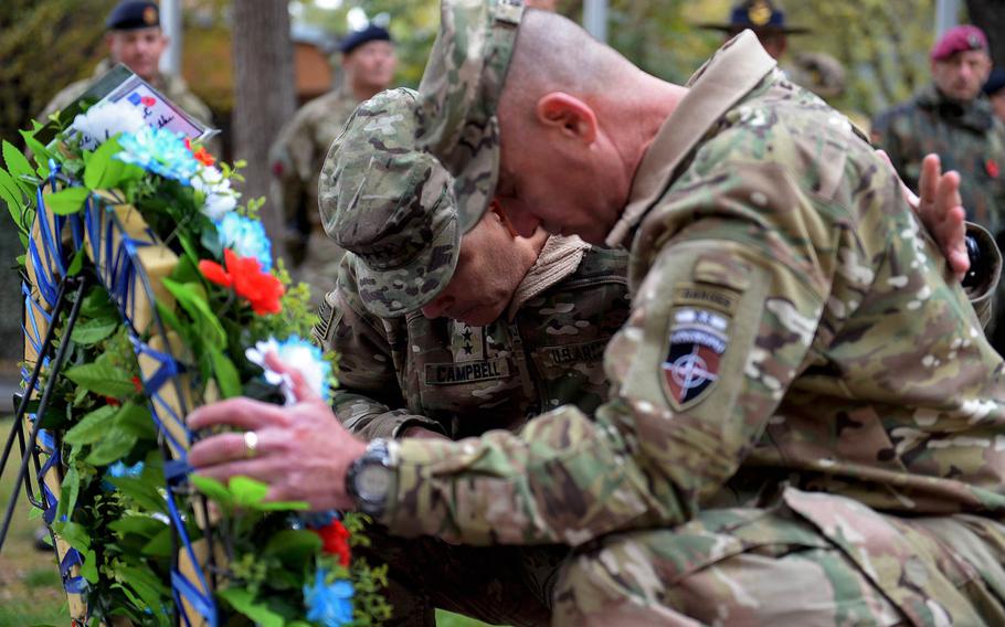 The top coalition and American commander in Afghanistan, Gen. John Campbell, left, and Command Sgt. Maj. Delbert Byers bow their heads after placing a wreath near a monument to fallen coalition and Afghan soldiers during a ceremony on Wednesday, Nov. 11, 2015, in Kabul.
