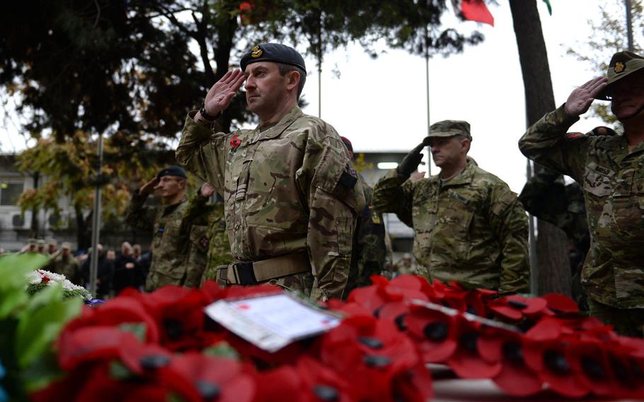 Coalition troops salute during a ceremony to honor fallen soldiers at the headquarters of the NATO-led Resolute Support mission in Kabul, Afghanistan on Wednesday, Nov. 11, 2015. The ceremony recognized victims of past wars, as well as the latest casualties of the war in Afghanistan.