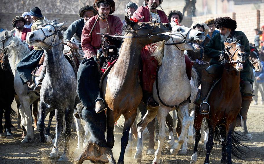 One rider, left, tries to keep a calf carcass from his competitors during a buzkashi match on the outskirts of Kabul on Jan. 15, 2015. The game involves almost constant contact between horses and their riders.