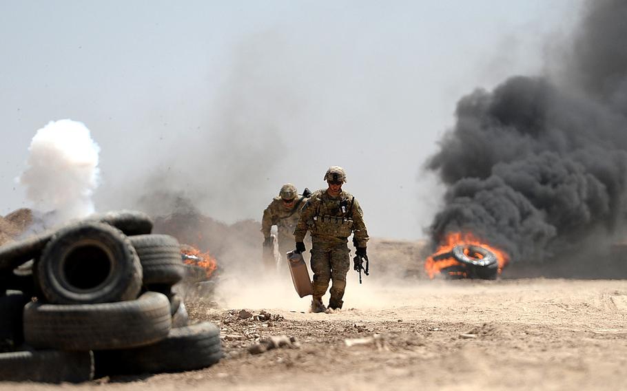U.S. Army advisers run to safety after lighting tires for realistic effects during an Iraqi army exercise at Besmaya, a coalition training site south of Baghdad on April 26, 2015.