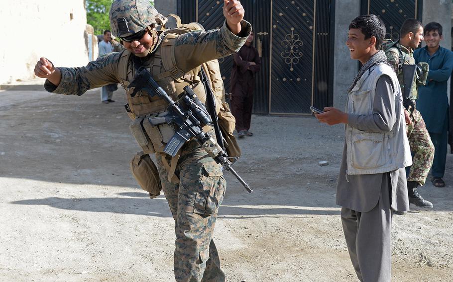 Petty Officer 2nd Class Christopher Johnson, a corpsman, dances along to a villager's cellphone music while on patrol near Bagram Air Field on May 9, 2015. About 50 Marines work with Georgian army partners to secure Bagram Air Field.