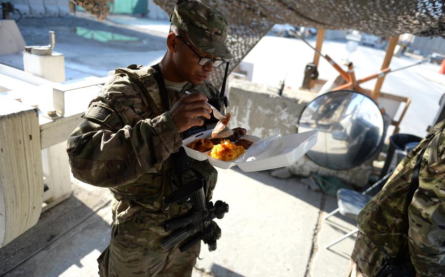 U.S. Air Force Airman 1st Class John Ross, 23, eats a Thanksgiving Day meal from a disposable container at a security checkpoint at Bagram Air Field in Afghanistan on Thursday, Nov. 26, 2015. On his first deployment, Ross said the holiday fare was better than the usual meals.
