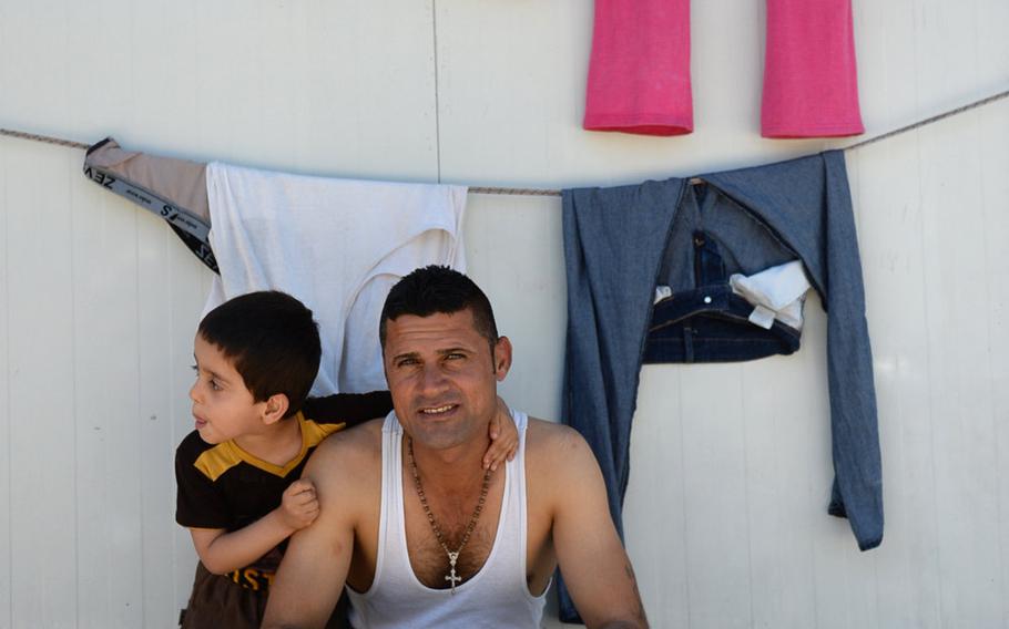 A man sits with his son at a Christian camp for internally displaced persons in Irbil, Iraq, in May 2015. The camp housed more than 270 families that fled Islamic State forces in northern Iraq.