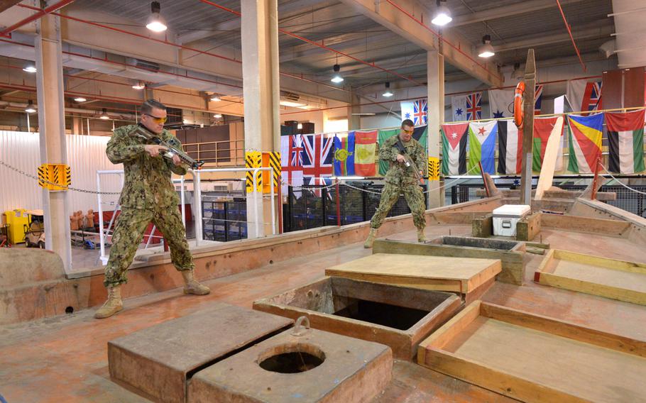 Coast Guardsmen Petty Officer 3rd Class Jake Brasker, left, and Petty Officer 2nd Class Philip Cook from Patrol Forces Southwest Asia's Maritime Engagement Team, demonstrate boarding procedures on a fishing dhow used to train U.S. and partner nations on boarding procedures in Bahrain, March 12, 2019. The facility is known as the ship-in-a-box and serves as platform for Coast Guard, Navy and partner nations to share best practices for visit, board, search and seizure tactics.