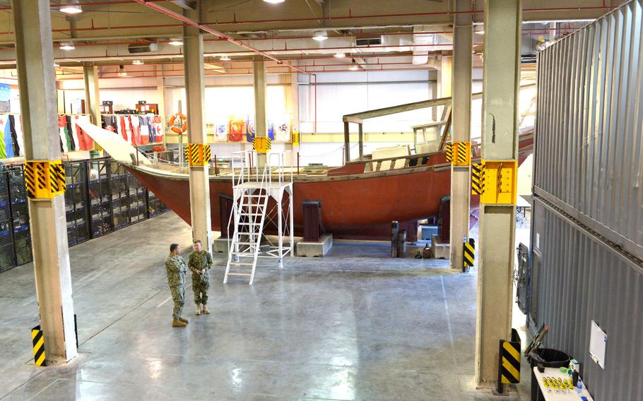 U.S. Navy and Coast Guard members talk by a fishing dhow used to train U.S. and partner nations on ship boarding procedures on March 12, 2019 in Bahrain.