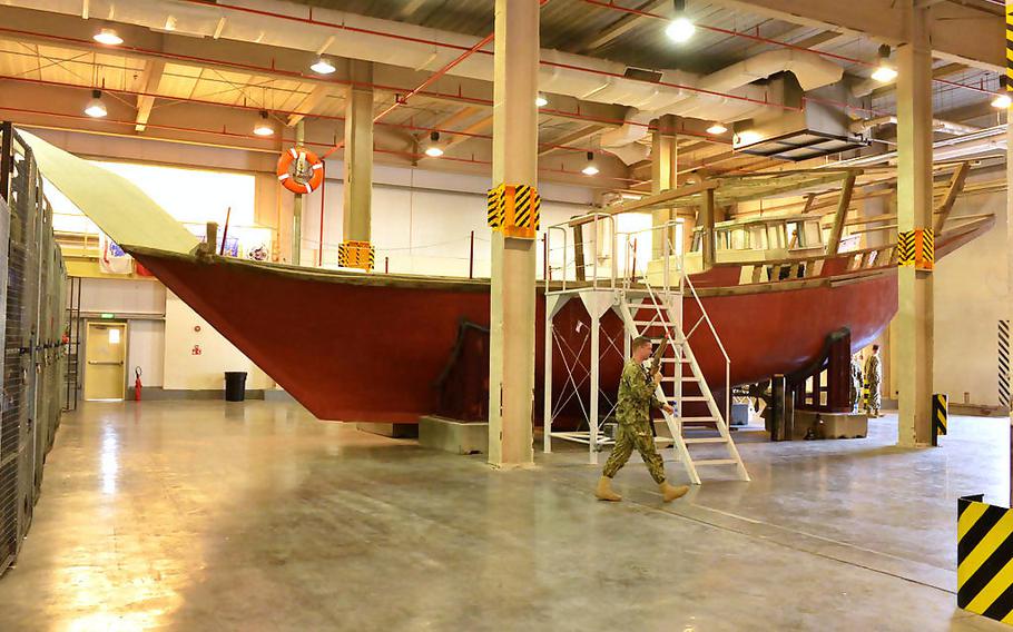 A Coast Guardsman from Patrol Forces Southwest Asia's Maritime Engagement Team walks past a fishing dhow used to train U.S. and partner nations on ship boarding procedures on March 12, 2019 in Bahrain.