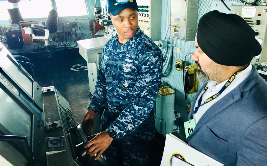 Petty Officer 2nd Class Dennis Johnson, a quartermaster aboard the aircraft carrier USS John C. Stennis, shows a journalist the ship's helm during a port visit to Bahrain on Monday, March 25, 2019.  Stennis' crew of approximately 5,000 sailors is in Bahrain for rest and relaxation during a scheduled deployment to both 5th and 7th Fleet areas of operations.