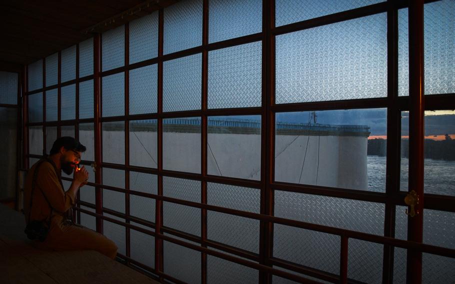 Chris Jones, who fought in two tours to Helmand province as a Marine, lights a cigarette as he watches the sun set over the river on a return trip to the province, April 16, 2019. Jones, now a photographer, returned to learn more about what happened to the province after he and other Marines left during the drawdown of international troops from Afghanistan.