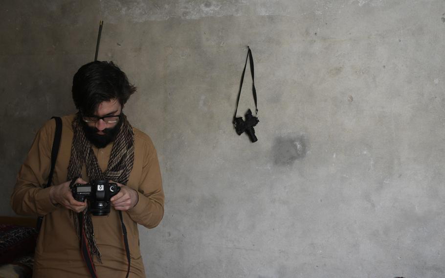 Low-light vision goggles hang from a hook near Chris Jones as the photographer examines his camera during a visit to an Afghan National Army base in Helmand province April 16, 2019. Jones, who fought in two tours to Helmand as a Marine, returned to learn more about what happened to the province after he and other Marines left during the drawdown of international troops from Afghanistan.