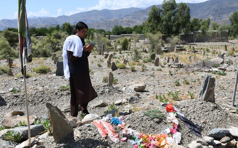 Afghan soldier Nematullah prays at a grave in his family's cemetery in Kunar province on Aug. 17, 2019. The family say they buried someone in the grave last year who they thought was him.