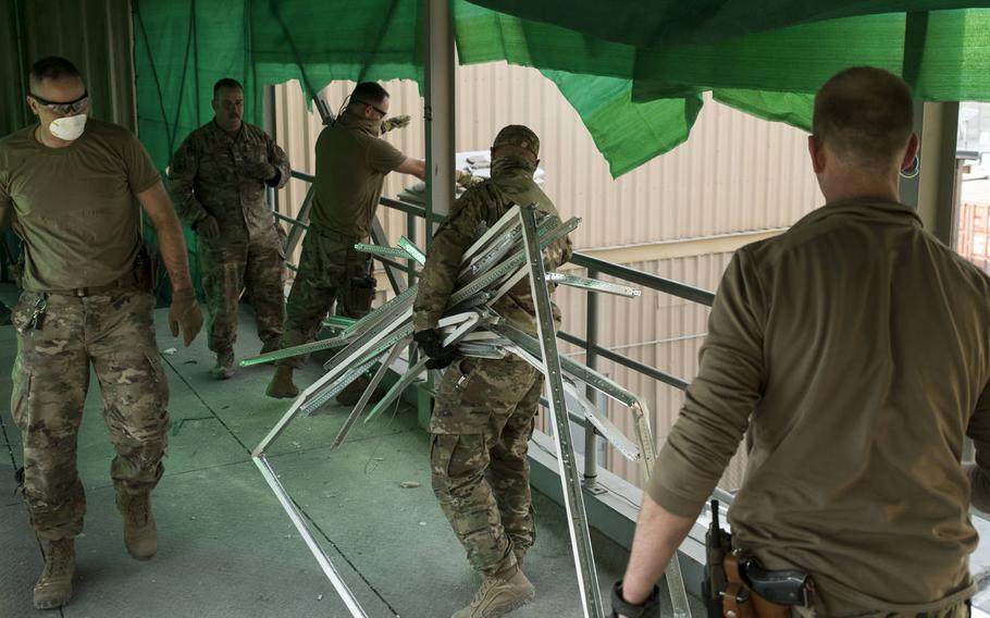 U.S. Air Force airmen from the 405th Expeditionary Support Squadron dispose of debris into a dump truck the day after a Taliban attack on Bagram Airfield, Afghanistan, Dec. 12, 2019.