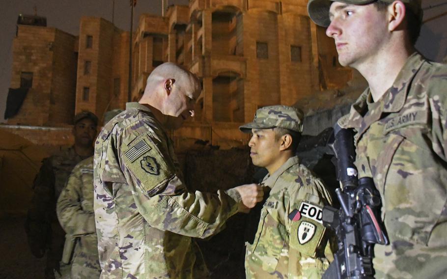 Col. Matthew W. Brown, commander of the 1st Stryker Brigade Combat Team, 25th Infantry Division, pins medals on Staff Sgt. Anthony Lee, left, and Spc. Logan Matthews during a ceremony at a camp in Mosul, Iraq, on Thursday, Dec. 26, 2019.