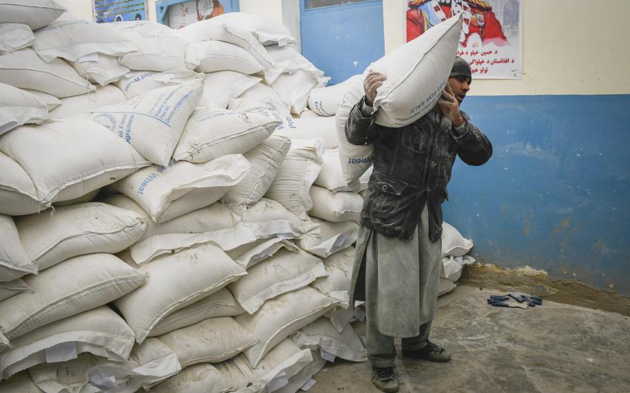 An aid worker hefts a 100-pound bag of wheat to be distributed by the United Nations World Food Program in Kabul, Afghanistan, Jan. 30, 2020. A third of the country's population may go hungry this winter, the U.S. Special Inspector General for Afghanistan Reconstruction reported.