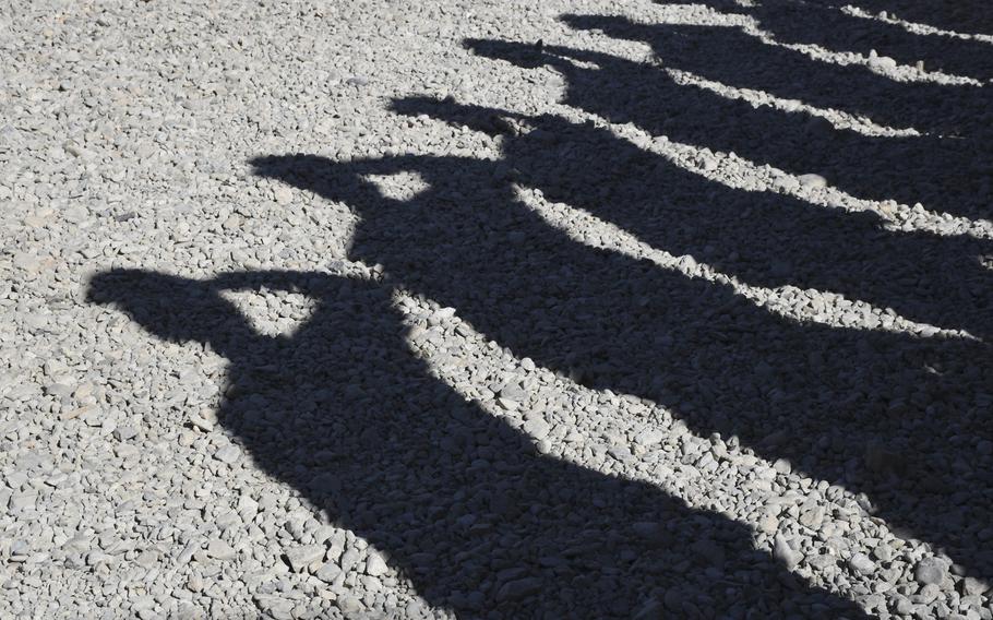 The shadows of a formation of Marines saluting are seen at Camp Shorab, Afghanistan, where U.S. military advisers will consolidate after closing a base in the nearby city of Lashkar Gah, beginning March 10, 2020, as part of a withdrawal deal with the Taliban.