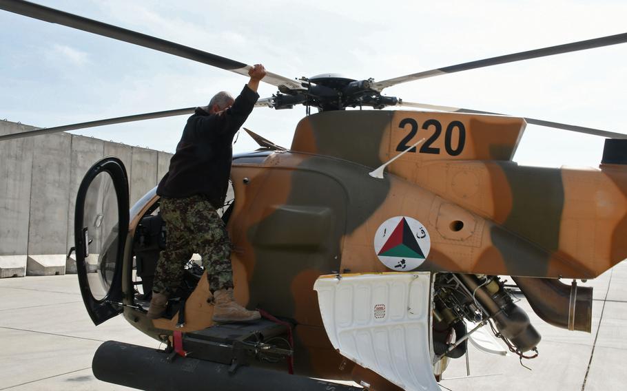 An Afghan maintainer inspects an MD-530 helicopter at Hamid Karzai International Airport in Kabul, Afghanistan, in  March 2018. The U.S. Army has awarded an additional $35 million to an Arizona company to support the Afghan air force's light attack helicopter fleet.