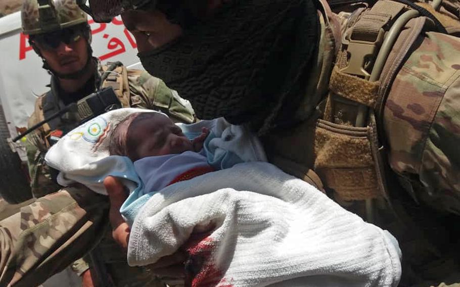 An Afghan police officer cradles an infant in his arms after rescuing the child from a hospital in Kabul that came under attack on Tuesday, May 12, 2020. It was unclear how many civilians died in the attack, but an Interior Ministry official said one of the assailants was killed in a firefight with police special forces.