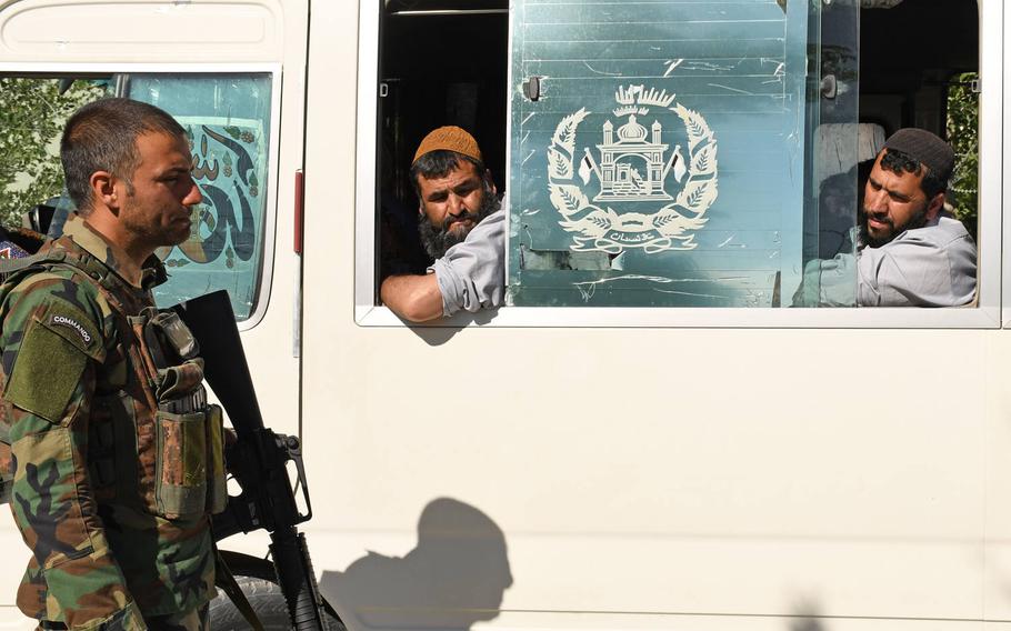 An Afghan commando exchanges a glance with recently freed Taliban prisoners outside Bagram prison on Tuesday, May 26, 2020. A U.N. report released this week said the Taliban has not severed ties with al-Qaida despite pledging to do so in a recent deal with the U.S.