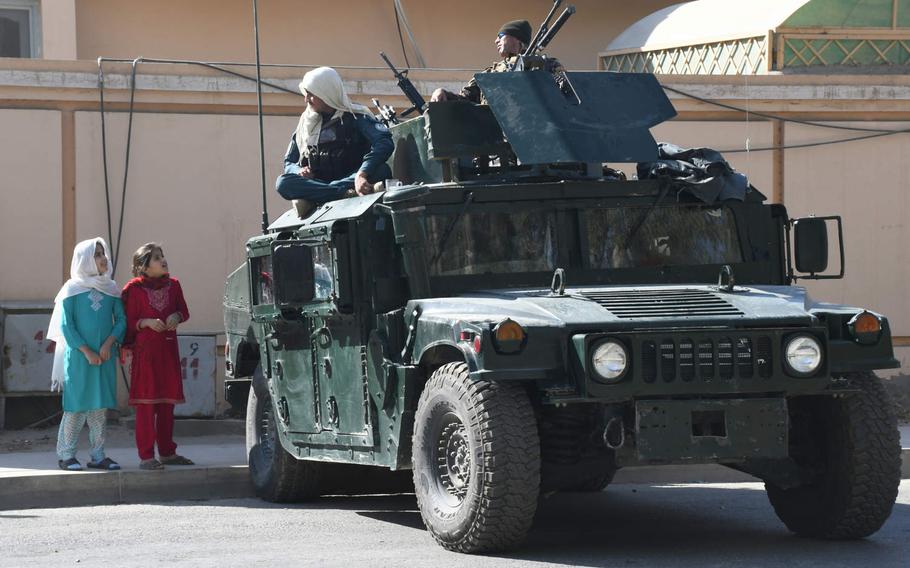 Two girls chat with security officials in Kandahar, Afghanistan, in October 2018. The Afghan War remains the world's deadliest conflict for children, according to a United Nations report released June 15, 2020.