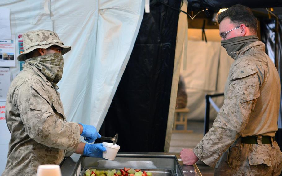 A U.S. Marine Corps volunteer prepares a meal for a fellow Marine at the Sandstorm field kitchen, Ahmed al-Jaber Air Base, Kuwait, April 17, 2020. The Sandstorm was stood up in an effort to further adhere to health protection levels by providing an additional avenue for customers to have a meal. A ''cluster'' of COVID-19 cases has developed at the base, officials said.