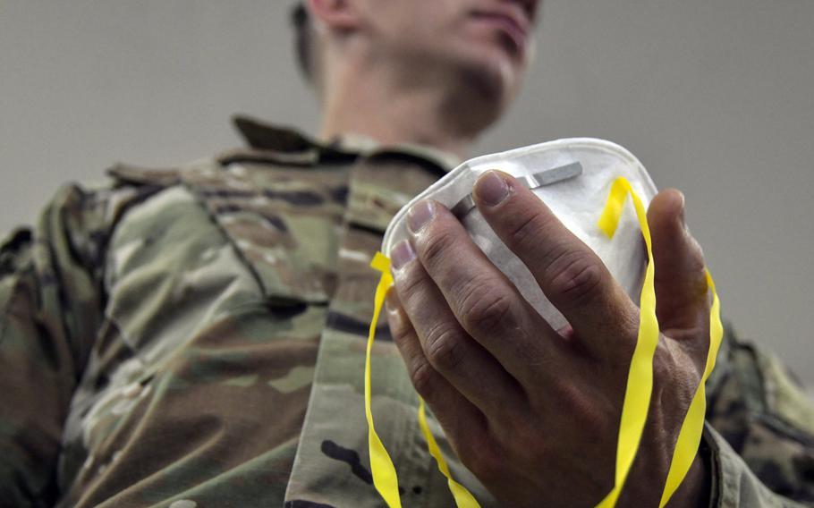 An airman assigned to 407th Expeditionary Logistics Readiness Flight adjusts the straps of his N95 mask to begin a fit test at Ahmed al-Jaber Air Base, Kuwait, March 13, 2020. A ''cluster'' of COVID-19 cases has developed at the base, officials said.