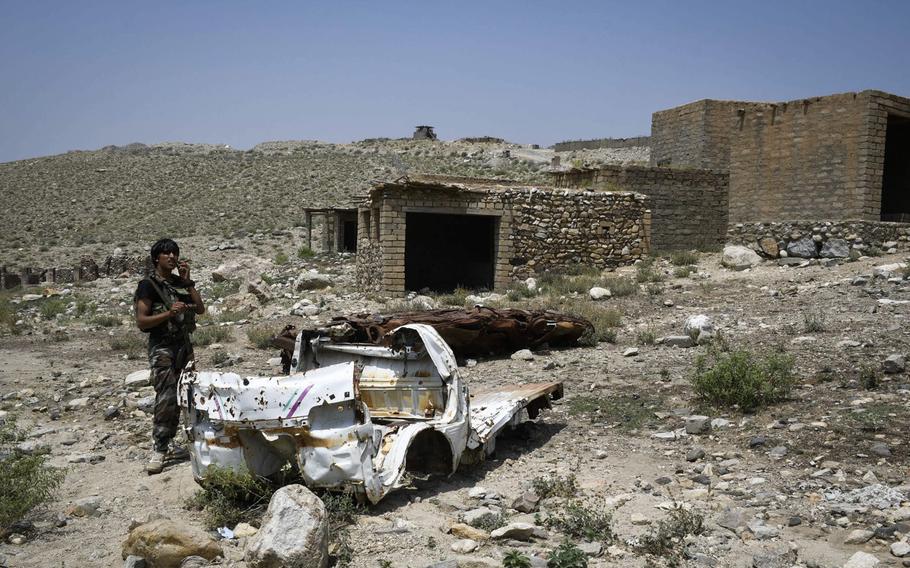 An Afghan militia fighter walks past two cars destroyed in an airstrike by the U.S. against Islamic State positions in the Achin district of Nangarhar provinc, Afghanistan on July 26, 2020. The surrounding market was also destroyed in the battle, locals said.