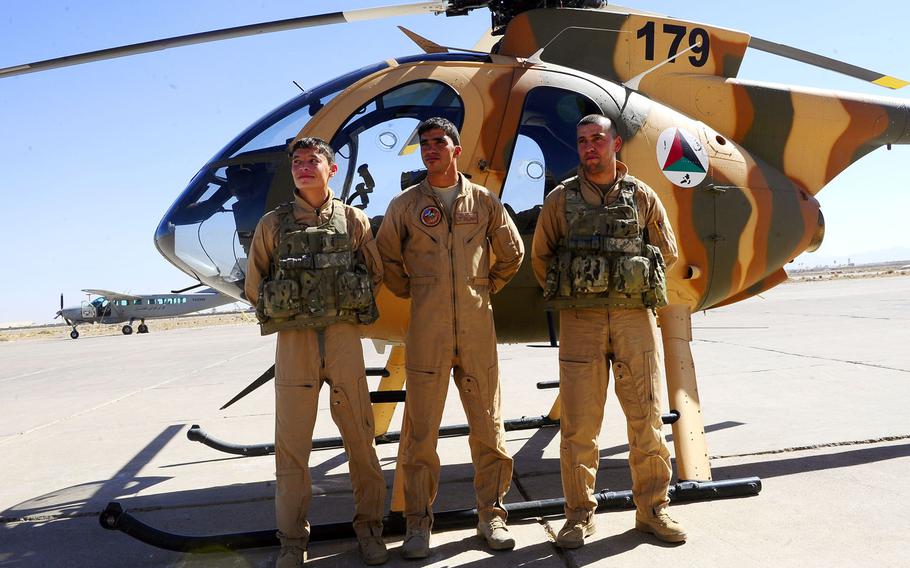 Afghan pilot Maj. Mohammad Naiem Asadi, left, and two other pilots pose for pictures after completing their first MD-530 helicopter solo flight, Oct. 16, 2012 at Shindand Air Base, Afghanistan. Asadi and his family had been approved to come to the U.S. for their protection until the Pentagon reversed its endorsement of their exit.