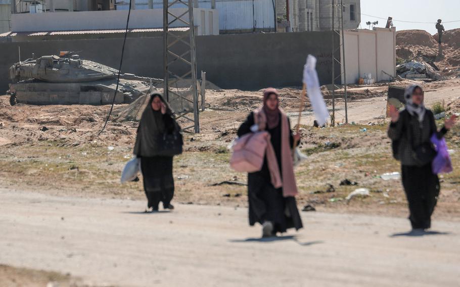 Displaced Palestinian women carrying their belongings lift a makeshift white flag as they walk past Israeli forces while fleeing the Hamad City area in Khan Yunis in the southern Gaza Strip on Tuesday, March 5, 2024, amid the ongoing conflict between Israel and the Hamas movement. 