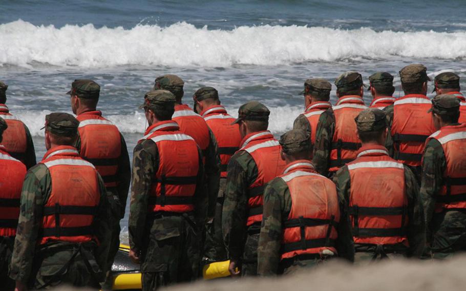 Navy SEAL candidates stand at attention on the beach