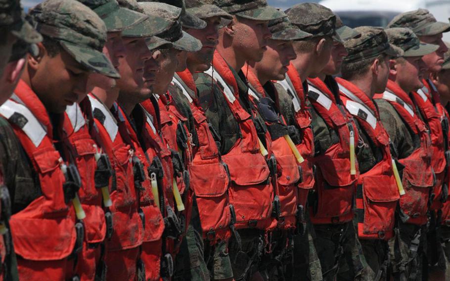 Sunburned Navy SEAL candidates stand at attention on the beach