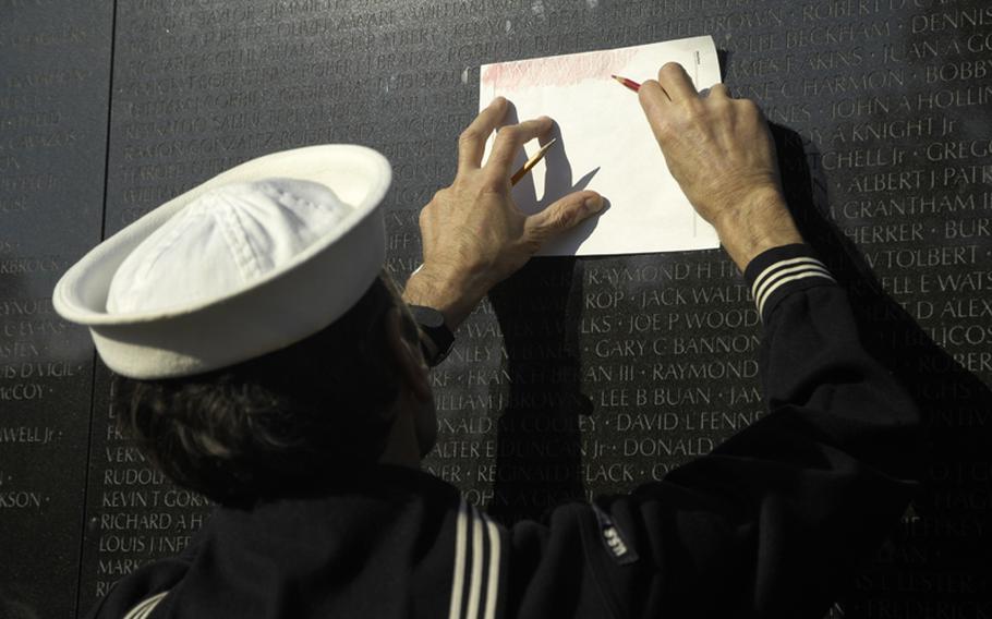 A visitor to the Vietnam Veterans Memorial on Nov. 11, 2012 makes a copy of a name on the wall.