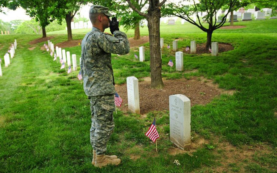Spc. Brock Bowers renders honors to Medal of Honor recipient Sgt. Dwight H. Johnson after placing a flag on his grave during "Flags In" in Arlington National Cemetery.
