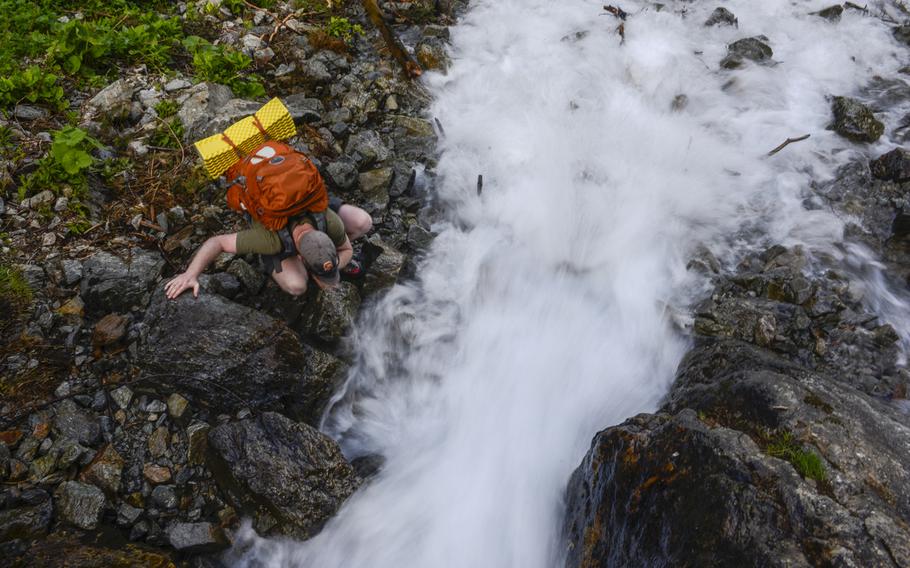 Matt Millham, a Stars and Stripes reporter, drinks from a mountain stream during an overnight hiking trip in Chamonix, France.

