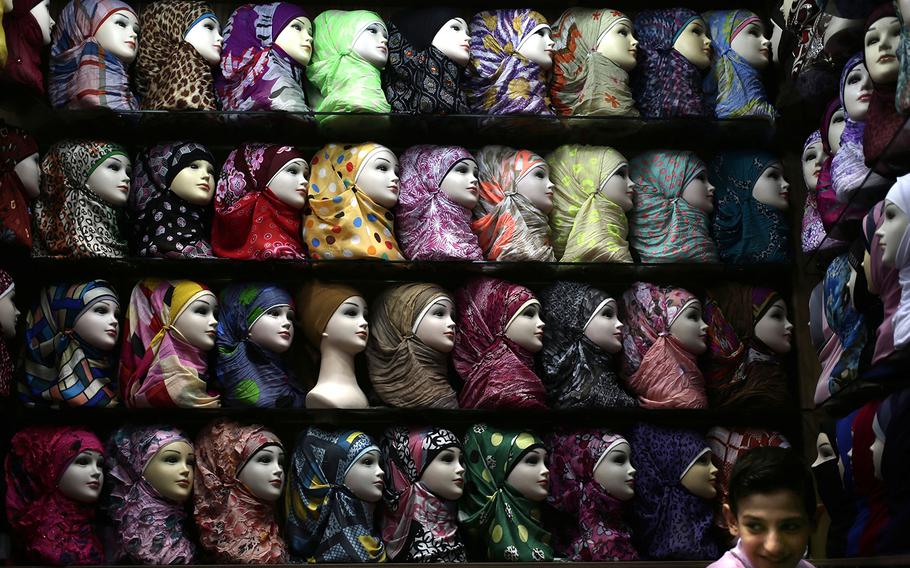A Syrian youth waits for customers in a shop selling head scarves at the popular Hamidiyeh old market.