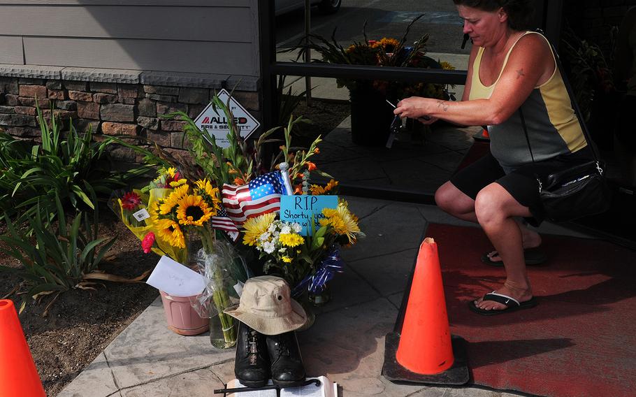 Lill Duncan takes a photo of a memorial for Delbert Belton, an 88-year-old World War II veteran who was beaten to death, in Spokane, Wash. 