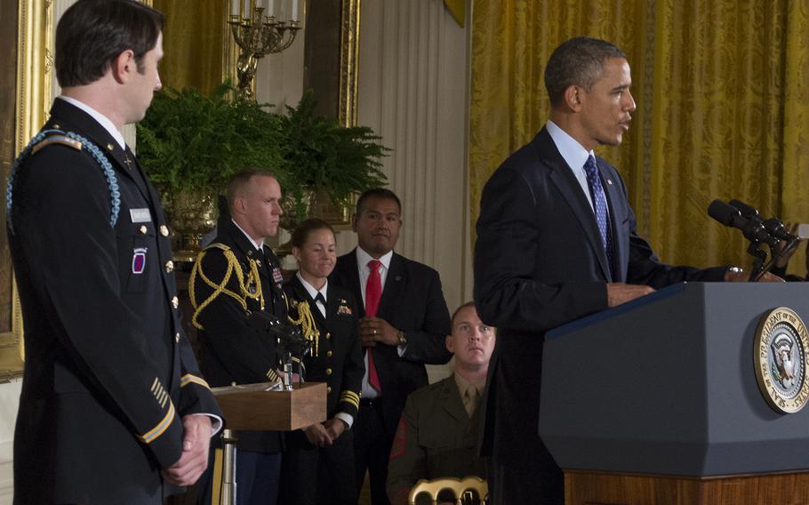 Capt. William Swenson listens as President Barack Obama talks about the battle in Afghanistan in which Swenson earned the Medal of Honor. 