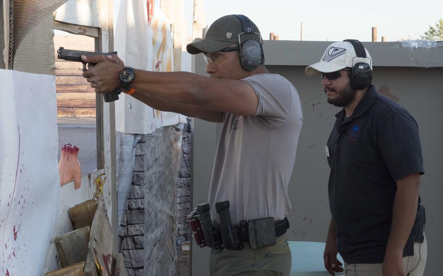 Ian Meyers of the U.S. Border Patrol engages paper targets while Israel Fornelli, a recreational aide with the Fort Bliss MWR, observes during the zombie shoot at the Rod and Gun Club at Fort Bliss, Texas, on Friday.