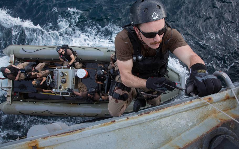 Ensign John Bozzelli climbs aboard the guided-missile destroyer USS Mason from a rigid hull inflatable boat.