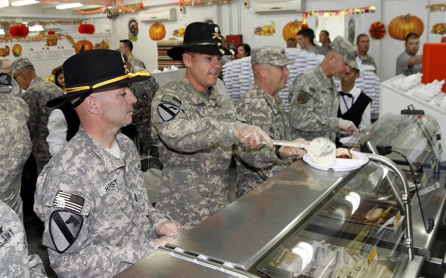 Command Sgt. Maj. Zacchaeus Hurst, left, and Lt. Col. Henry Perry, right, of the 4-227th Attack-Reconnaisance Battalion, 1st Cavalry Division serve Thanksgiving lunch to soldiers at Camp Buehring in Kuwait.  