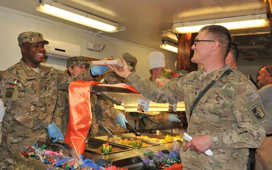 Command Sgt. Maj. Christopher T. Crawford, the 101st Special Troops Battalion command sergeant major, gives Spc. Victor W. Stephans, a mechanic with Task Force Lifeliner, his tray of food while serving lunch at the Koele Dining Facility during Thanksgiving Day, Nov. 28, 2013, at Bagram Air Field, Parwan province, Afghanistan.