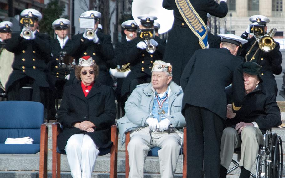 Pearl Harbor survivors Howard Snell, sitting left in the grey jacket, and Major Albert Grasselli receive coins during the Pearl Harbor Remembrance Day on Dec. 7, 2013, at the U.S. Navy Memorial in Washington, D.C.