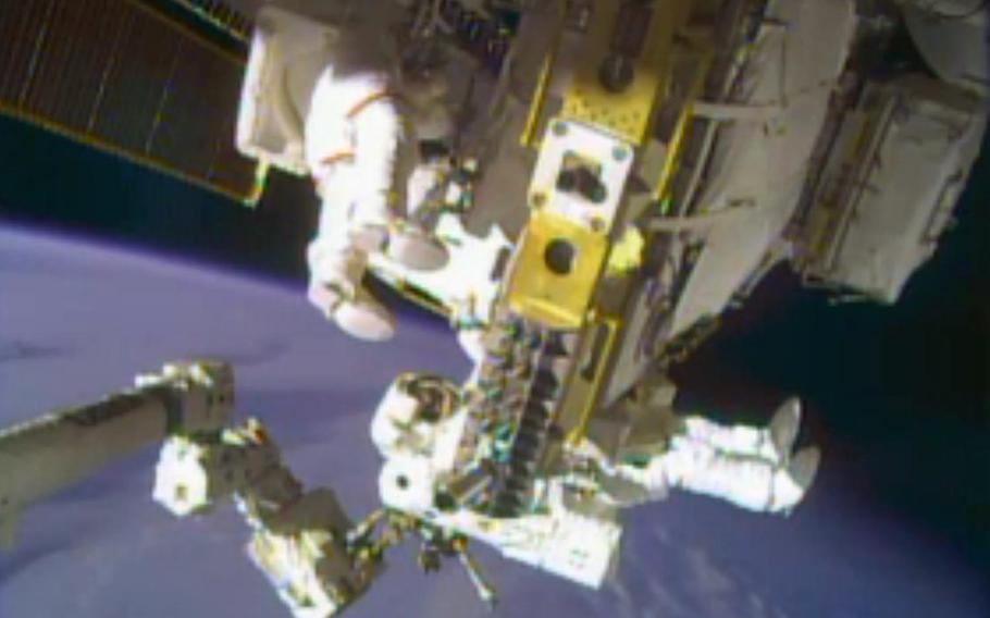 In this image taken from video provided by NASA, astronauts Rick Mastracchio, top, and Michael Hopkins work to repair an external cooling line on the International Space Station on Monday, Dec. 24, 2013, 260 miles above Earth. The external cooling line - one of two - shut down Dec. 11. The six-man crew had to turn off all nonessential equipment, including experiments.