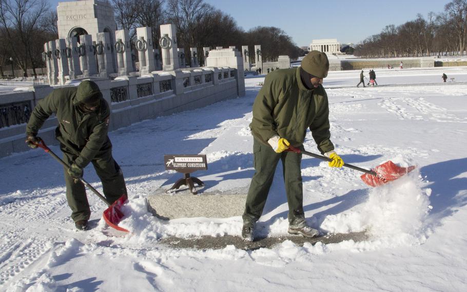National Park Service workers clear snow from the National World War II Memorial in Washington, D.C. in the wake of Winter Storm Janus, on January 22, 2014.