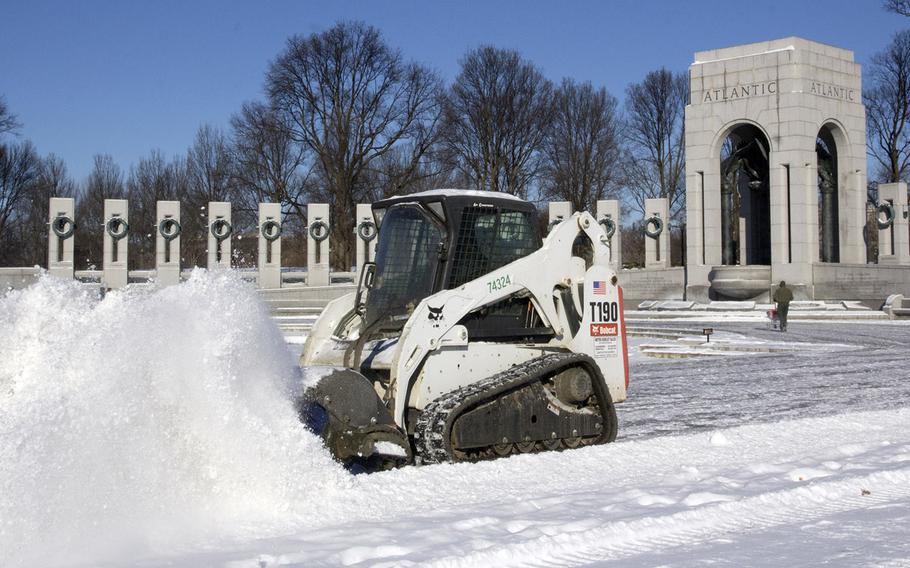 National Park Service workers clear snow from the National World War II Memorial in Washington, D.C. in the wake of Winter Storm Janus on January 22, 2014.
