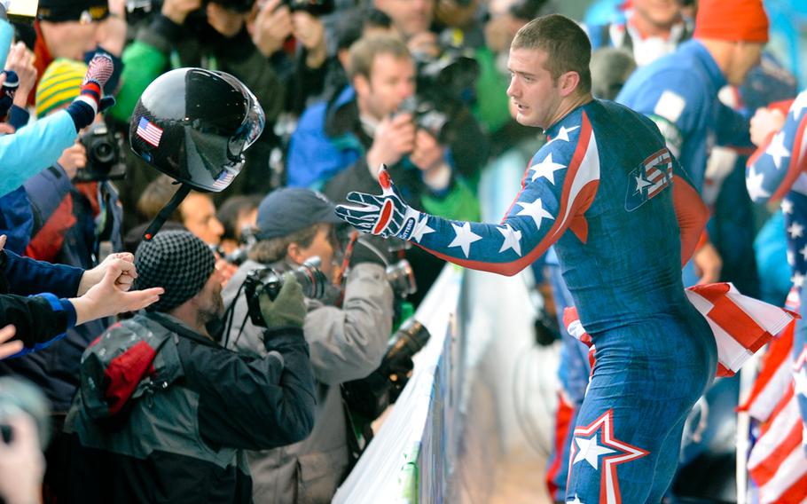 Justin Olsen of USA-1 four-man bobsled team tosses his helmet to a fan after the team won gold in men's four-man bobsled in Whistler, Canada, on Saturday, February 27, 2010.