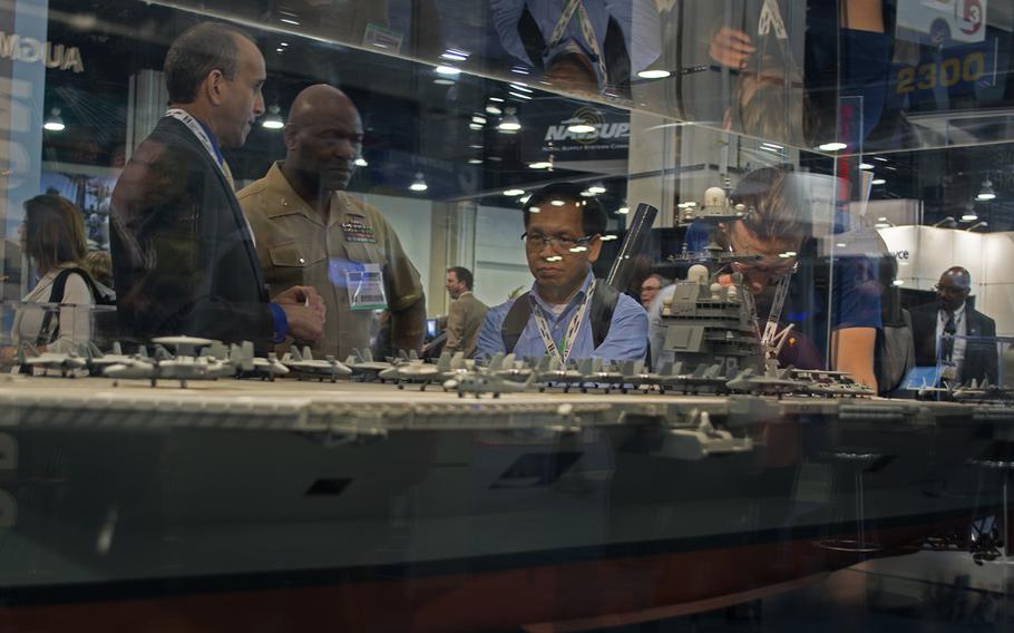 Several people are seen through the glass of a ship display at the Sea-Air-Space convention in Maryland on April 8, 2014.