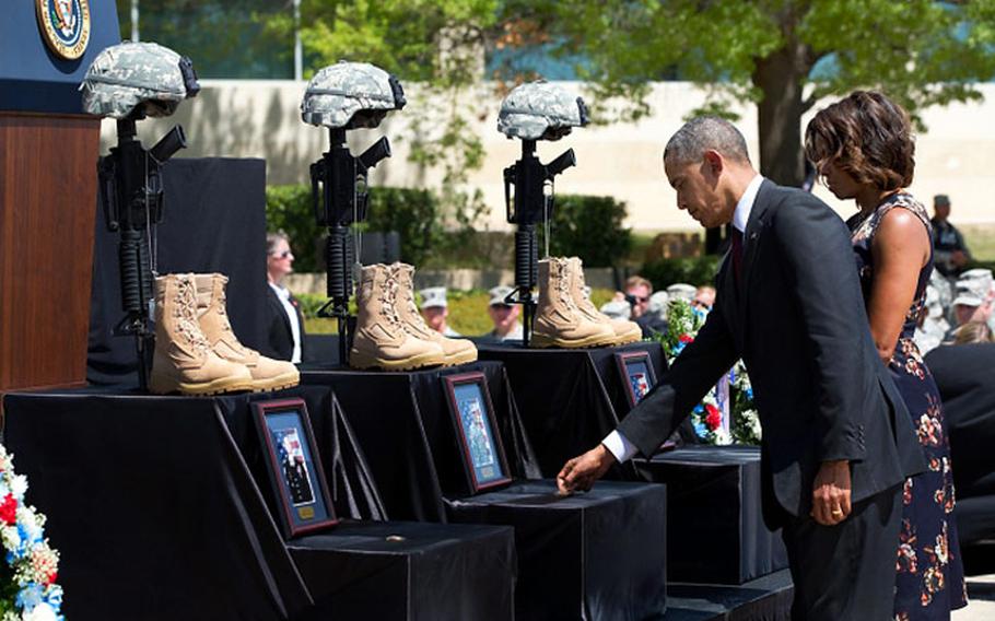 During a memorial service Wednesday, April 9, 2014, on Fort Hood, Texas, President Barack Obama, with first lady Michelle Obama, places a coin on each of the 3 boxes for the soldiers who died during the April 2 shooting rampage.