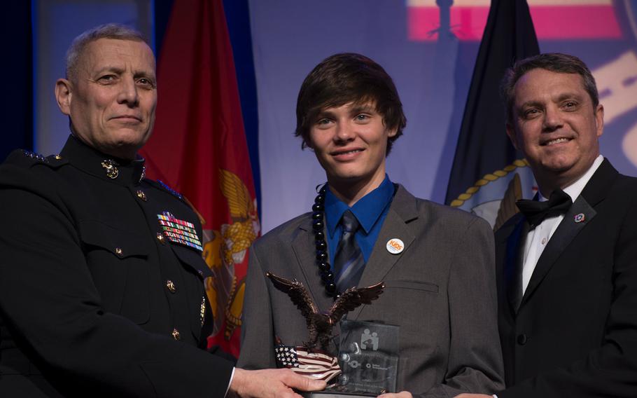 Michael-Logan Burke Jordan, center and representing the Marine Corps, poses for a photo after receiving his Military Child of the Year award from Assistant Commandant of the Marine Corps, left. 