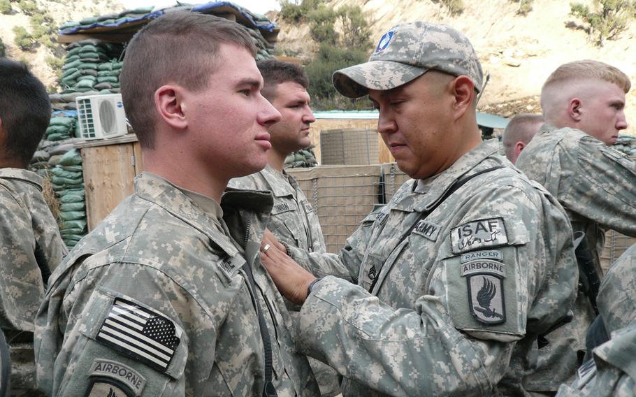 Staff Sgt. Conrad Begaye awards Spc. Kyle White the Combat Infantryman Badge during a ceremony in Nuristan Province, Afghanistan, Nov. 6, 2007.