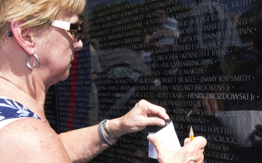 Sophia Drozdowski prepares to make a pencil rubbing of the name of her husband, Henry, on the Vietnam Wall after a ceremony on May 11, 2014 marking the addition of 13 names.